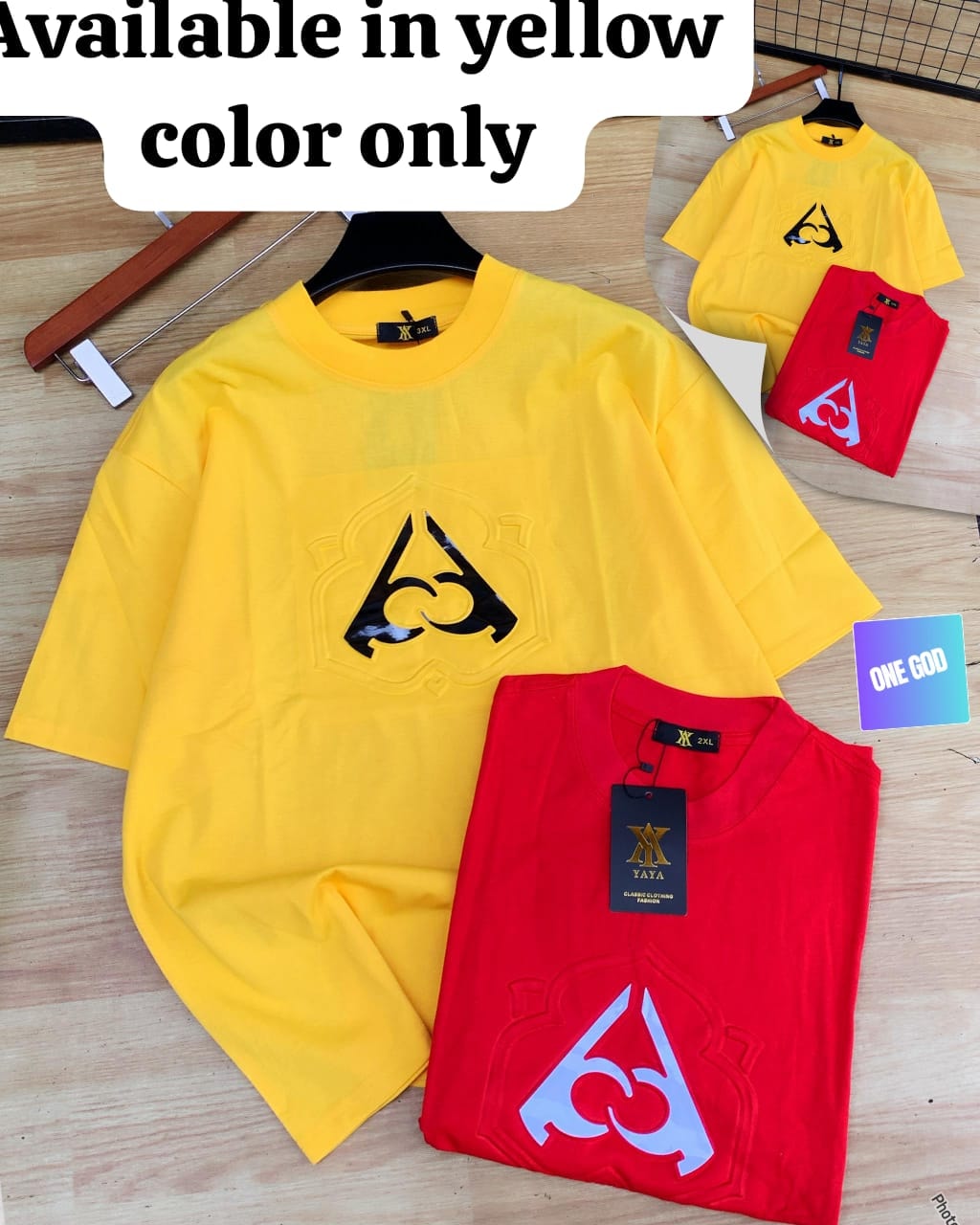 Yellow embroidered logo tee with red reference on wood surface.